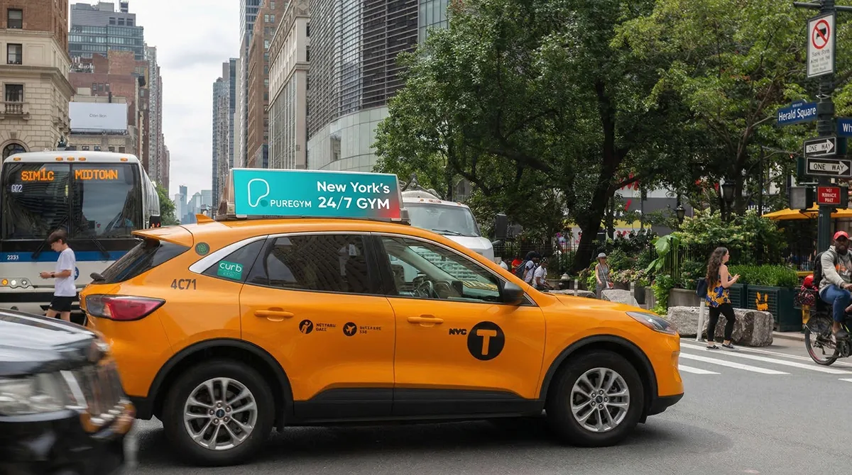A digital taxi top screen running a gym advertisement on a yellow cab at Herald Square, New York