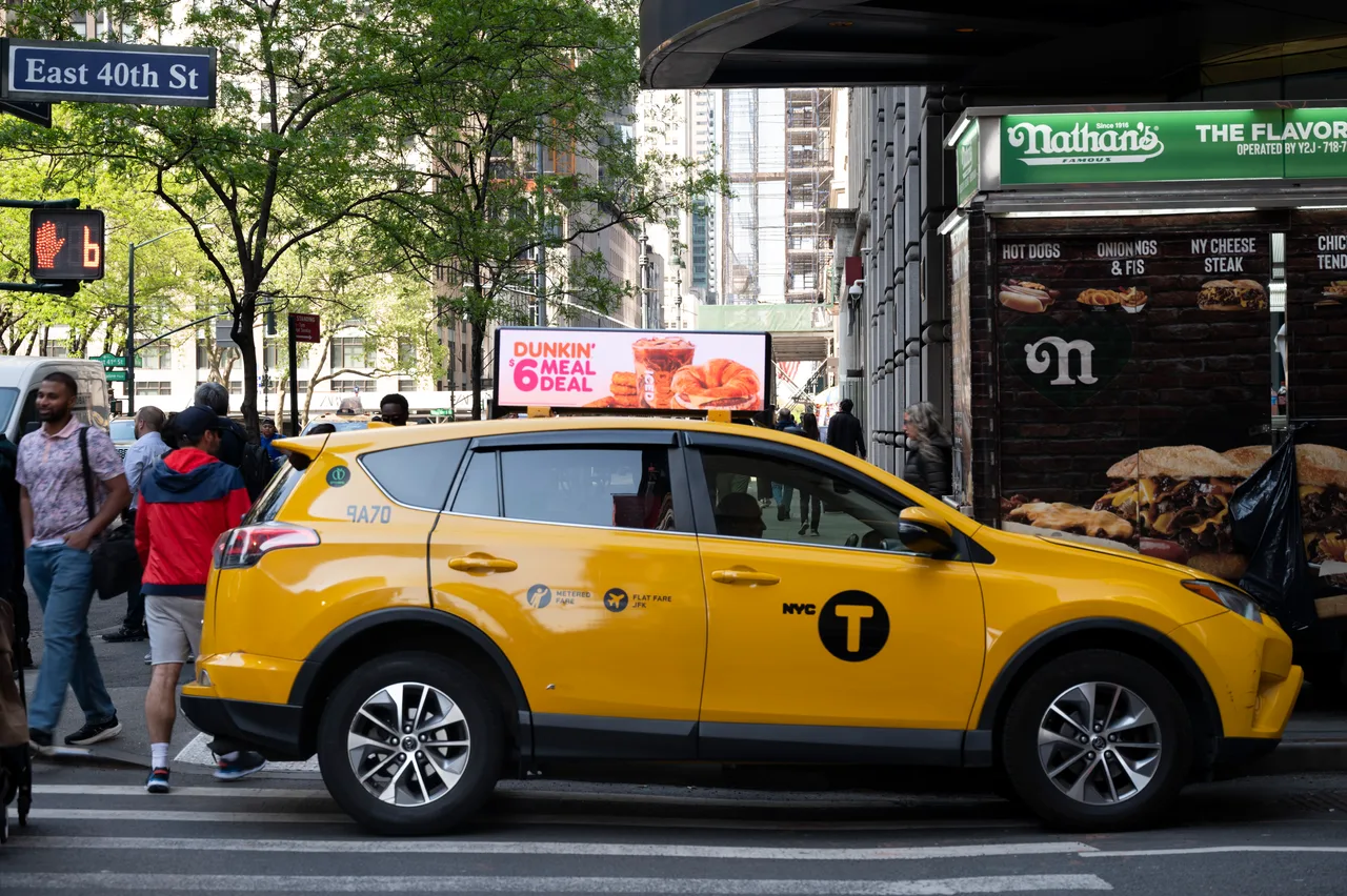 Dunkin' digital taxi top on a yellow New York taxi at the East 40th Street crosswalk in Manhattan